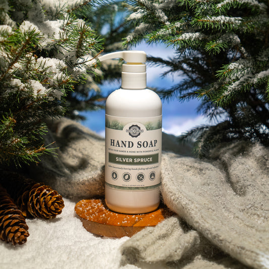 Rustic Strength, Hand Soap, 16oz bottle labeled 'Silver Spruce' in a snowy landscape with pine cones and evergreen branches.