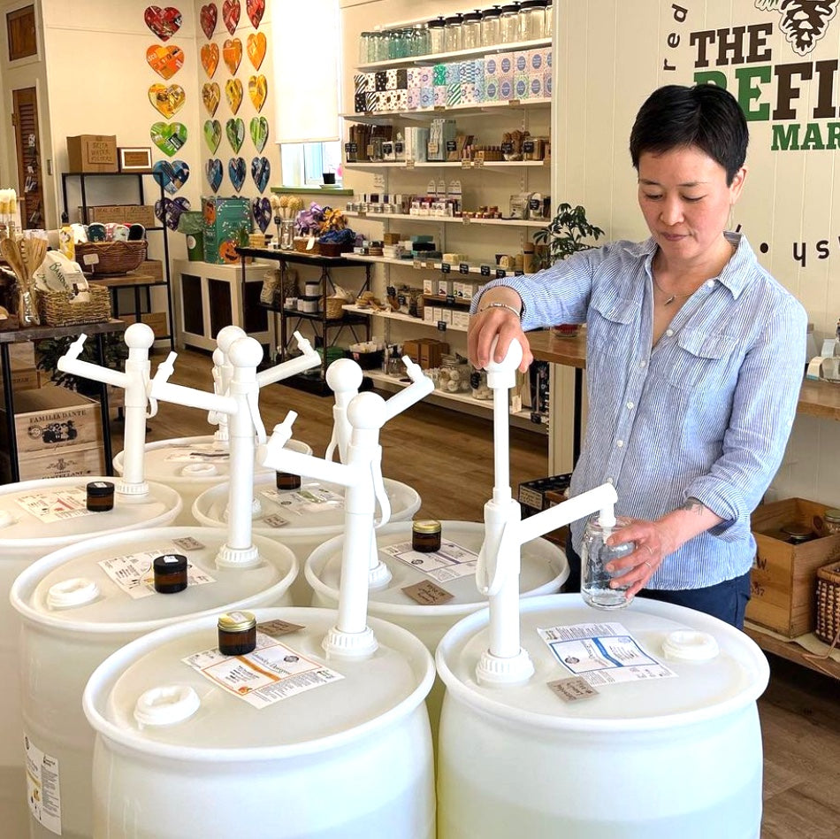Rustic Strength, Interior of a Refillery with a customer filling a bottle from a drum