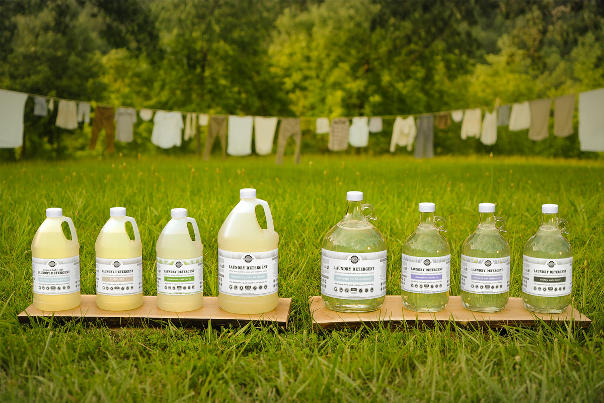 Rustic Strength, Lineup of Laundry Detergents in both Plastic and Glass packaging on grass lawn with laundry line in background