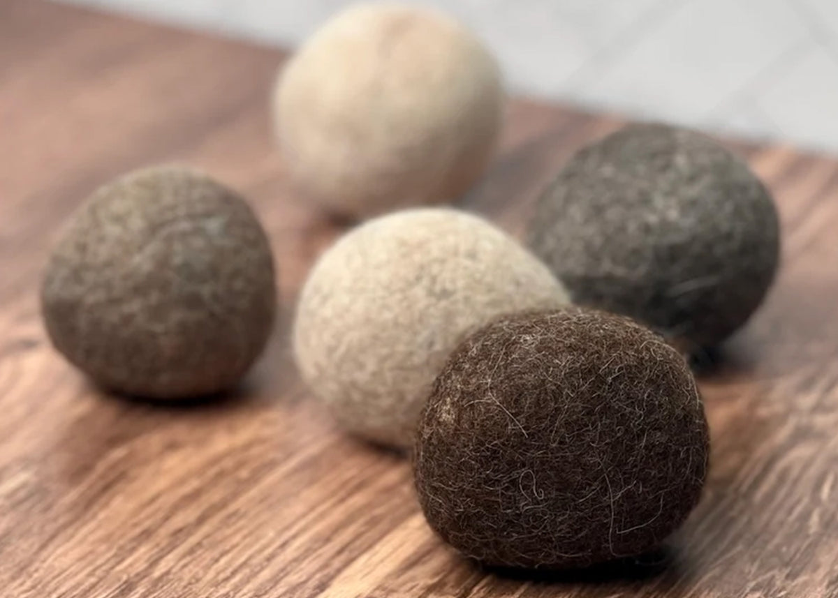 Rustic Strength, Five wool felt balls in various earthy tones, including dark brown, medium brown, beige, and gray, arranged on a wooden surface.